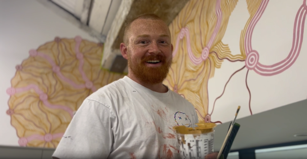 Wiradjuri and Ngiyampaa artist Matthew “Melnunnie” Brettschneider creating a mural at Screenrights’ office